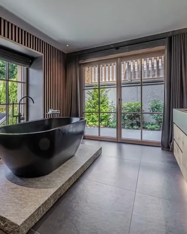 Foto: Badezimmer mit freistehender schwarzer Badewanne und Fenster zum Garten