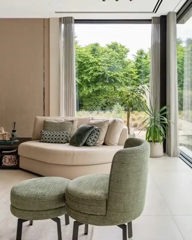 Foto: Wohnbereich mit hellem Sofa, grünen Sesseln und grosser Fensterfront
